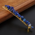 Macro shot of blue raw crystal stones hand-wrapped on a golden metal hairpin - Lapis Lazuli + Gold Clip