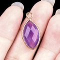 Marquise purple amethyst pendant with golden metal frame held between fingers - Amethyst