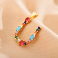 Macro shot of gold letter U pendant with colorful zircon stones on champagne fabric - Letter U