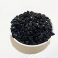 Polished black irregular natural crystal gravel in a white dish on wood background - Black Tourmaline