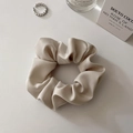Detail of elegant champagne satin silk scrunchie with soft folds and minimalist props - Medium Beige (approx. 10CM)
