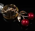 Glittery dark red cherry bag charm with golden leaves and lobster clasp on black background - Red Cherry with Large Double Leaves (Light Gold)