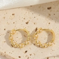 Detailed close-up of golden twisted hoop earrings with white pearls on a stone surface - Gold Twisted Pearl Hoop