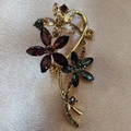 Close-up of vintage flower brooch with purple crystals and gold alloy base on pink satin - Purple