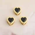 Detailed view of three golden heart-shaped pendants with black cubic zirconia stones - Black