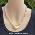 Detalle de collar de perlas de 8mm con colgante de corazón dorado mate puesto en modelo - 8mm / Dorado