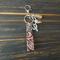 Détail d'un porte-clés en cuir avec pendentif tête de taureau, cactus et pompon sur bois - Tête de Taureau Khaki Gland