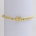 Golden beaded bracelet with a polished capital letter W charm on a white display stand - Gold W