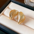 Macro shot of gold shell-shaped earrings with striped texture on a beige jewelry tray - Shell Threaded Brushed Style (30#)