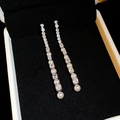 Eleganti orecchini a nappa in argento con zirconi e perle su sfondo di velluto nero - Argento
