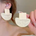 Gros plan de boucles d'oreilles bohèmes en rotin avec clous carrés et pendentifs tissés - 22# Tige en argent - Carré blanc demi-cercle tissé paille