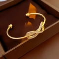 Detalle de brazalete bañado en oro con pavé de piedras en un diseño de nudo entrelazado - Dorado