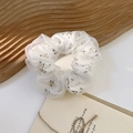 Detail eines floralen Organza-Haargummis mit doppellagigem Netzstoff auf einem Holzbrett - Blumenmuster Gelb