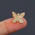 Detailed close-up of a tiny golden butterfly ear stud with clear zircon on a fingertip - 1# Butterfly / Gold
