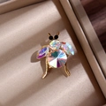 Gros plan d'une broche insecte dorée avec cristaux irisés dans un écrin à bijoux - Doré
