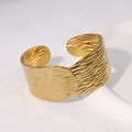 Golden wide open cuff bracelet with water ripple texture on white stone background - Gold