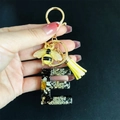 Detail of resin letter E keychain featuring real dried flowers, gold foil, and a bee charm - Letter E