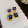 Detailed close-up of vintage gold earrings with deep blue gemstones on white velvet - Deep Blue Rectangular Gemstone Gold Base