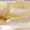 Elegant gold chain necklace featuring white Baroque pearls on a cream silk background - H58 Seven Pearls Delicate Necklace Gold