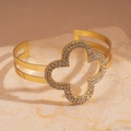 Close-up of gold double-layer open bangle featuring a sparkling diamond-set clover charm - Gold