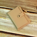 Dettaglio del portafoglio beige minimalista con cerniera in metallo e fibbia su legno - Cachi