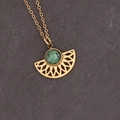 Close-up of golden sunflower pendant with green gemstone on a textured stone surface - Fan Green