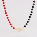 Dettaglio di perline sfaccettate rosse e nere con collana pendente a cuori intrecciati oro - Collana Doppio Cuore con Perline Rosse e Nere