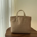 Detail of woven straw tote bag with brown leather handles and rivet accents - Camel
