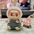 Labubu doll in white bunny hood and grey overalls with a peach charm accessory - Pinkish-gray Sweatshirt / First And Second Generation Keychains Are Compatible With La Cloth Dolls. Dolls Not Included.