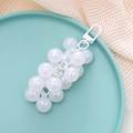 Dettaglio di un portachiavi a uva con perle bianche iridescenti su un piatto verde - Ciondolo / Bianco