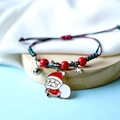 Close-up of a festive red and green woven Christmas bracelet with Santa Claus charm - Santa Giving Gifts