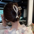 Elegant gold fish-shaped hair claw clip with pearls and rhinestones on a bun hairstyle - Fish Shape Gold Metal Pearl Claw