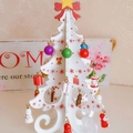 Miniature white wooden Christmas tree with festive ornaments and a red bow - White