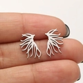 Macro shot of silver hollow feather earrings in stainless steel on hand for size - Tree Branch / Steel