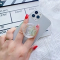 Detail shot of a clear glitter phone grip featuring gold stars and a green planet design - Transparent Earth