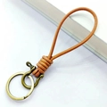Porte-clés en cuir tressé marron avec boucle fer à cheval en laiton sur fond blanc - Cuir Naturel Boucle Fer à Cheval Bronze