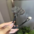 Vue détaillée du fer à friser feuilles en strass avec perle sur tige métallique souple - Lys Noir Fusil