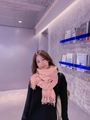Pink cashmere-feel knit scarf with fringes worn by a model in a modern room setting - Nude Pink