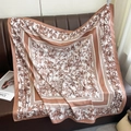 Detail of silk-like square scarf featuring brown bamboo leaf print on a leather sofa - Rose Gold