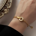 Pulsera dorada de doble cadena con círculo de nácar blanco y grabado BELOVE - Pulsera dorada con nácar blanco circular y pedrería