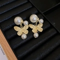 Detail of golden butterfly earrings with faux pearls on a black jewelry tray - Gold Butterfly Pearl Drop Earrings