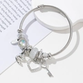 Detail shot of silver charm bracelet with heart, key pendants and sparkling crystal beads - White