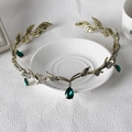 Detailed close-up of golden leaf bridal tiara with green teardrop crystal accents - Bronze with Green Gemstone