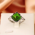 Detailed close-up of a silver ring featuring a large square-cut green gemstone on silk - Sugar Tower Square Gem / Green