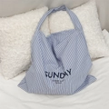 Detail of blue and white striped canvas tote bag with Sunday Summer Night text on a white bed - Blue Stripe