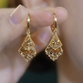 Detail of gold rhombus earrings with sparkling inlaid gems held by fingers - Gold Full Zirconia