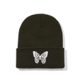 Close-up of a white butterfly embroidery on an olive green ribbed knit beanie hat - One Size / Black