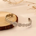 Dettaglio di un bracciale aperto in acciaio argento con ciondoli a moneta stile sole - Argento Trama del Sole