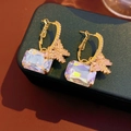 Detailed close-up of golden bow earrings with rectangular iridescent gems on green velvet - Gold (S925 Silver Pin)