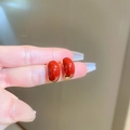 Détail de boucles d'oreilles vintage rouges et dorées tenues entre les doigts - Style de Haricot (24#)